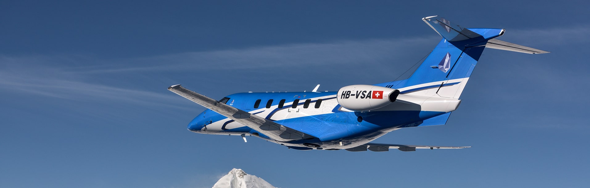 A pilatus PC-24 flying over moutains