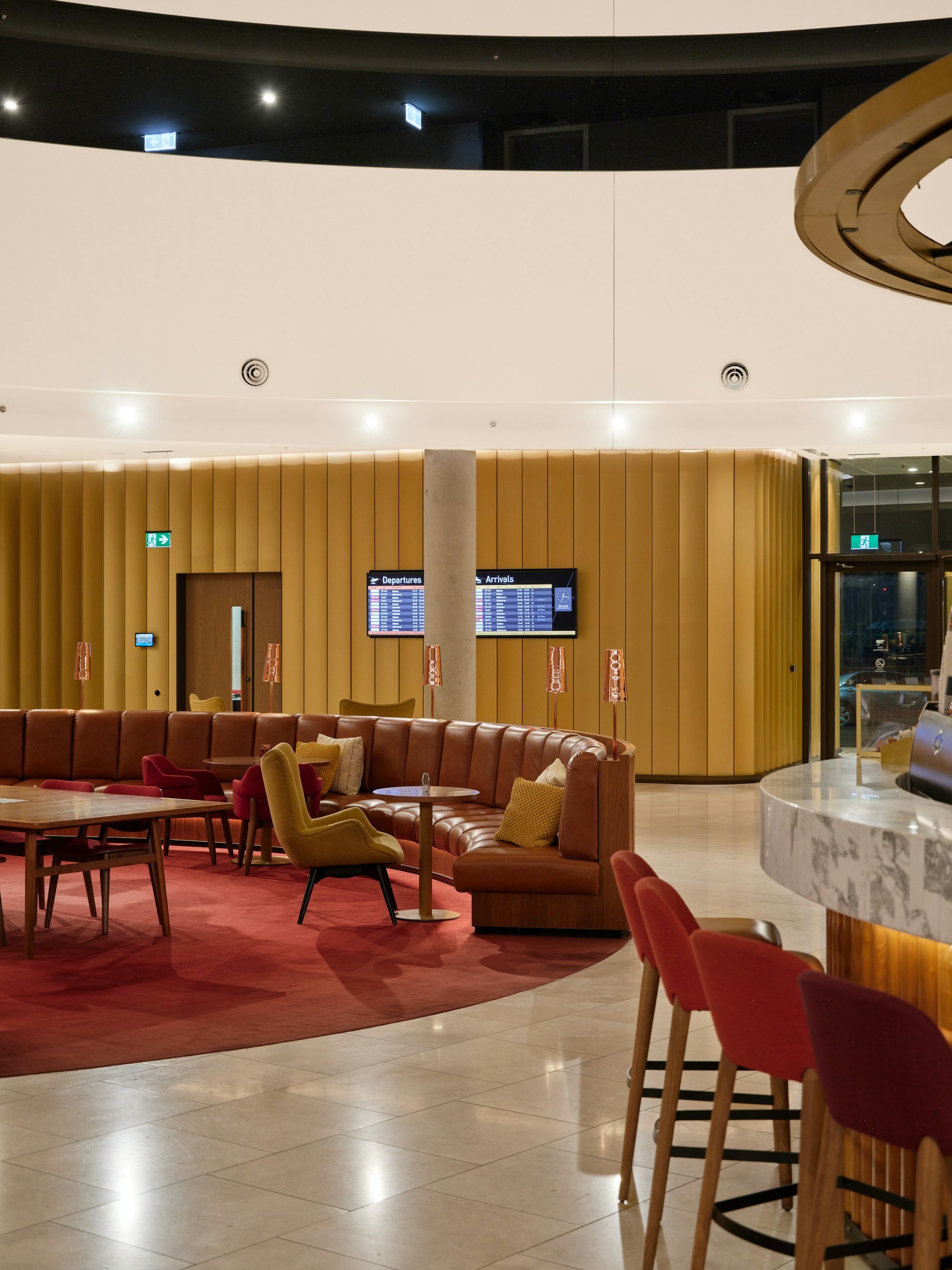 Upscale airport lounge with curved seating, bar and flight information screen Upscale airport lounge with curved seating, bar and flight information screen