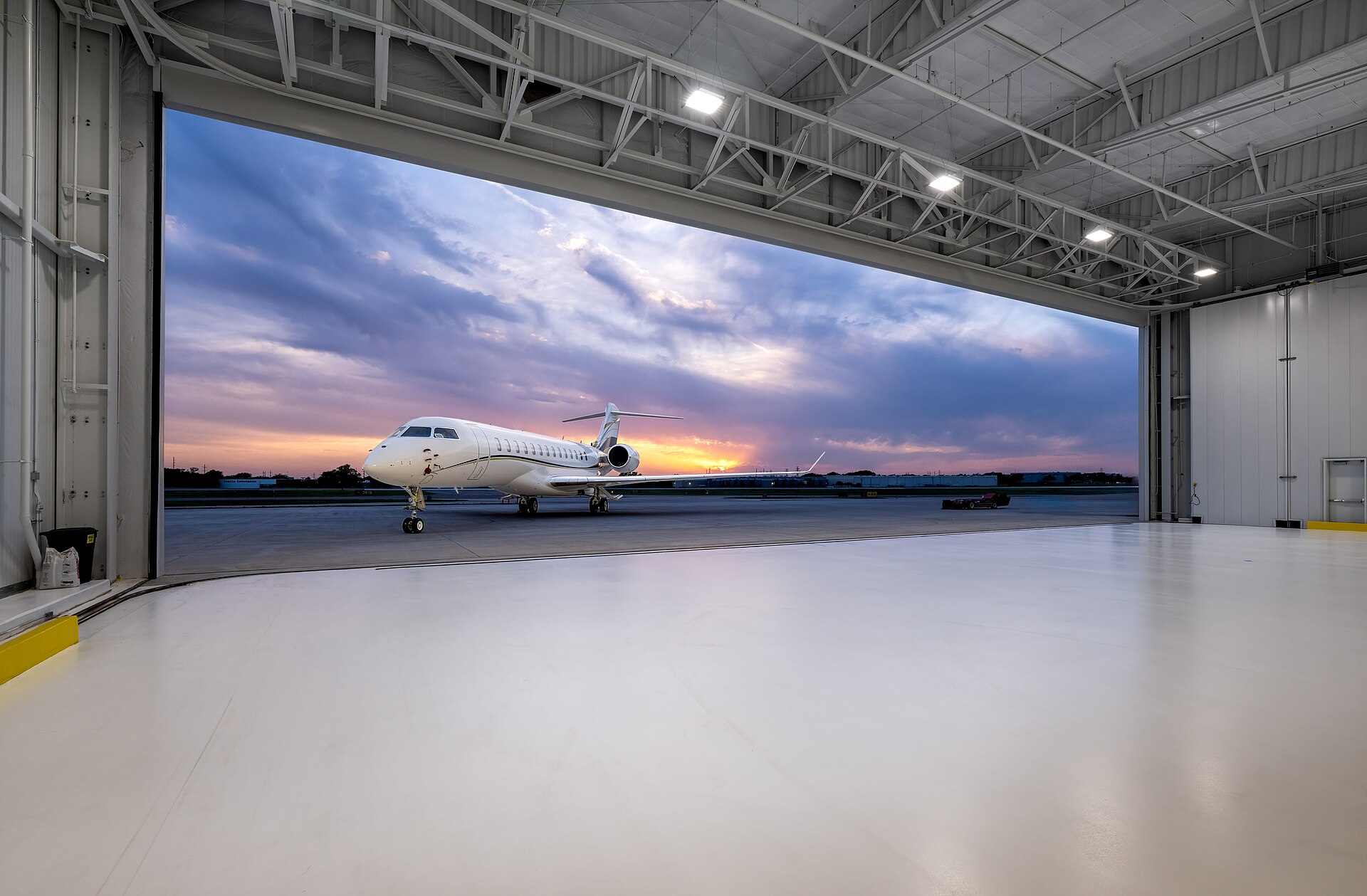 Business jet on the apron seen from inside a maintenance hangar, the setting of a pre-purchase inspection Business jet on the apron seen from inside a maintenance hangar, the setting of a pre-purchase inspection